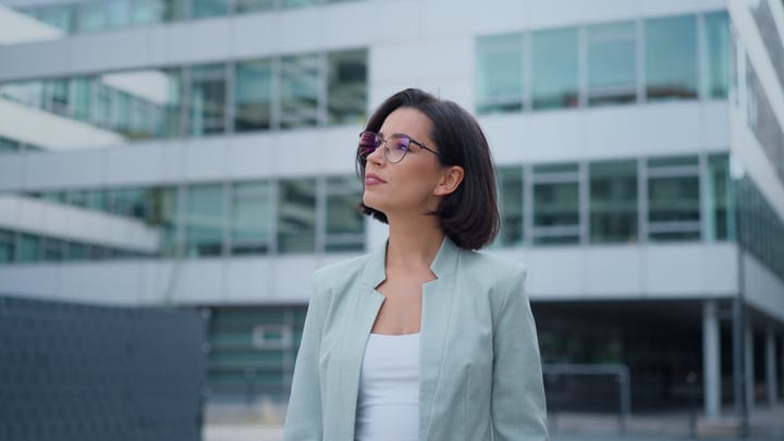 Confident Businesswoman Reflects Outside Modern Office Building
