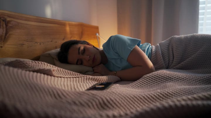 Young Woman Sleeping Soundly In A Cozy Bed In Her Modern Apartment